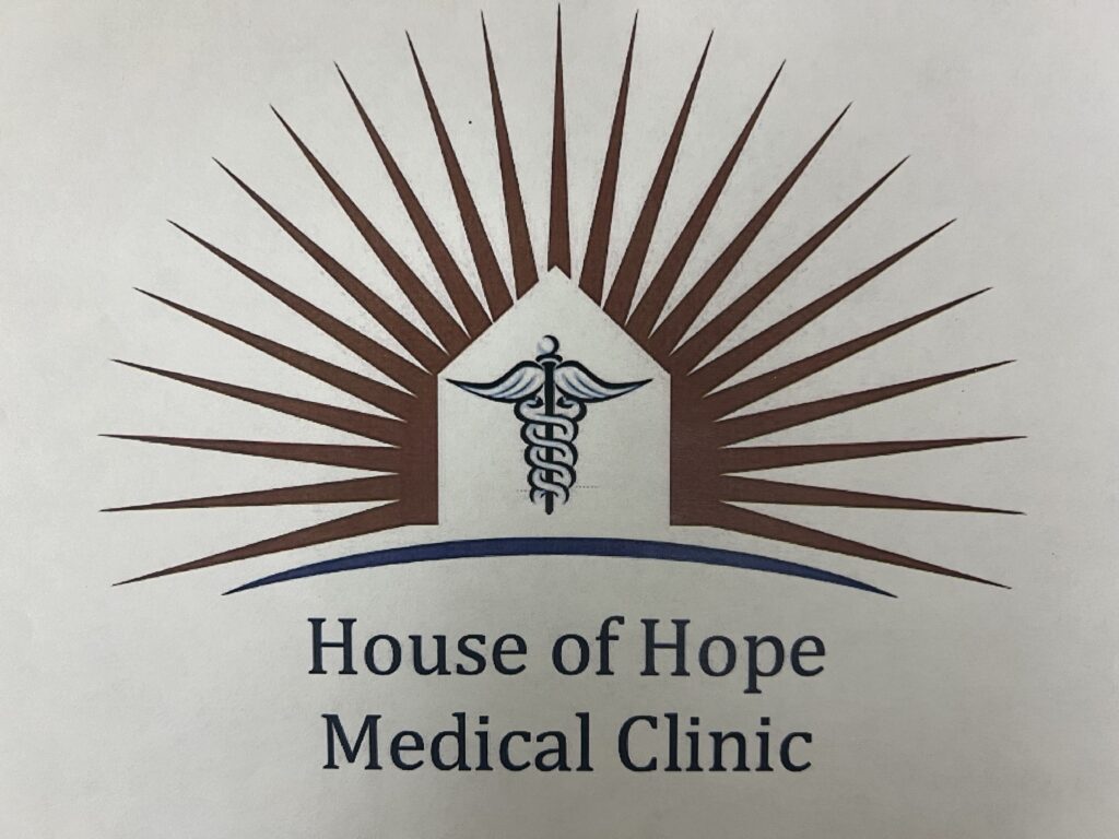 The Arundel House of Hope Medical Clinic logo. An outline of a house with a medical symbol inside. Around the house there are orange rays of light. It says House of Hope Medical clinic. 