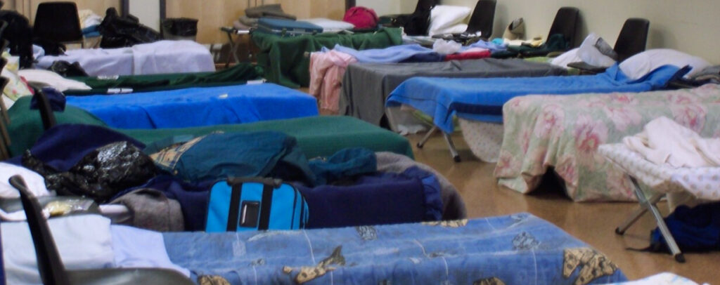 Cots with sleeping bags line a church. Church host Winter Relief 