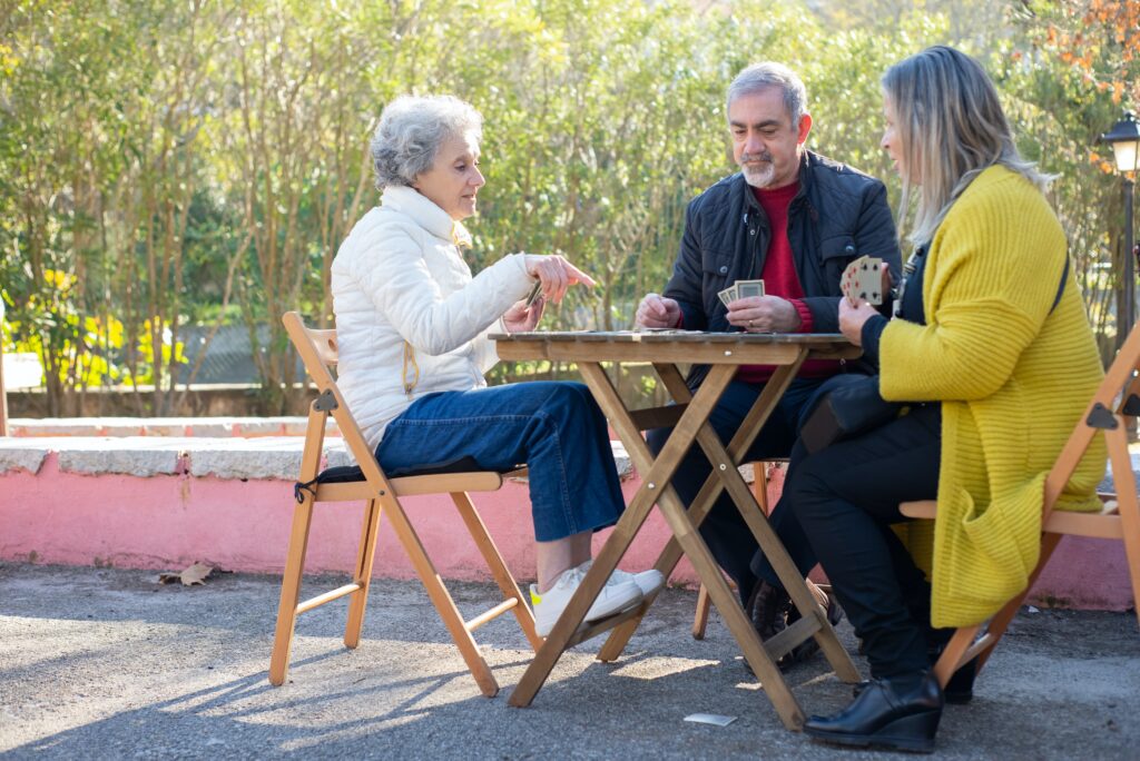 Two women and man playing card games. The community recovery center offers social activities for people in recovery and for people experiencing homelessness 