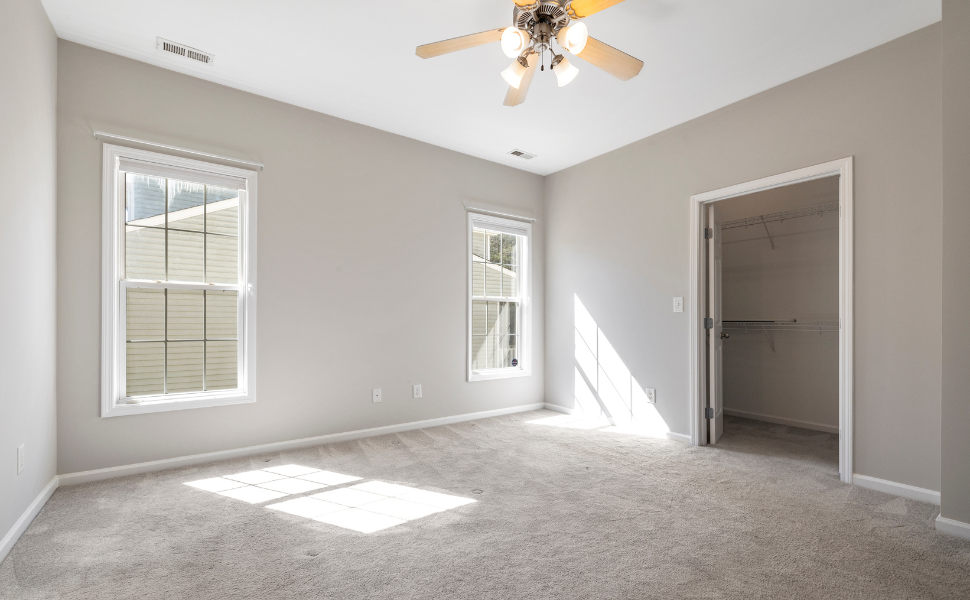 An empty apartment living room with carpet, two windows, a closet, and ceiling fan. Receiving housing after being homeless is a big milestone. 