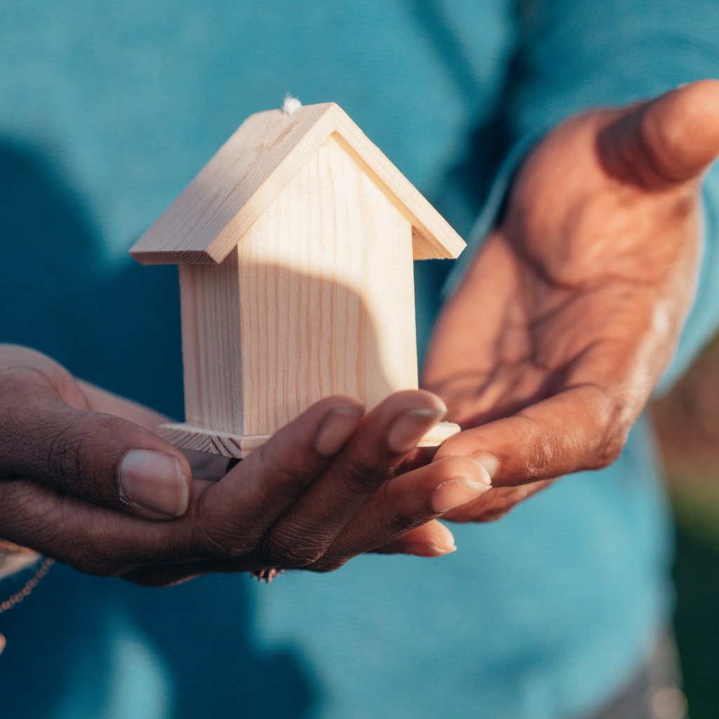 A person holding a miniature house. Anne Arundel County Maryland has a lot of resource for people facing eviction, homelessness, food insecurity, and other challenges. 