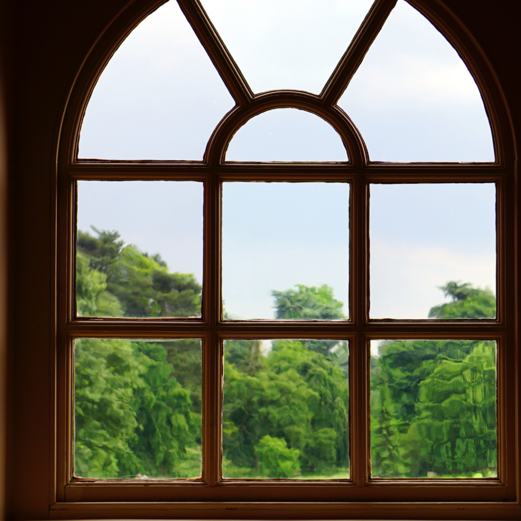 A curved window with a view of green trees in the background.