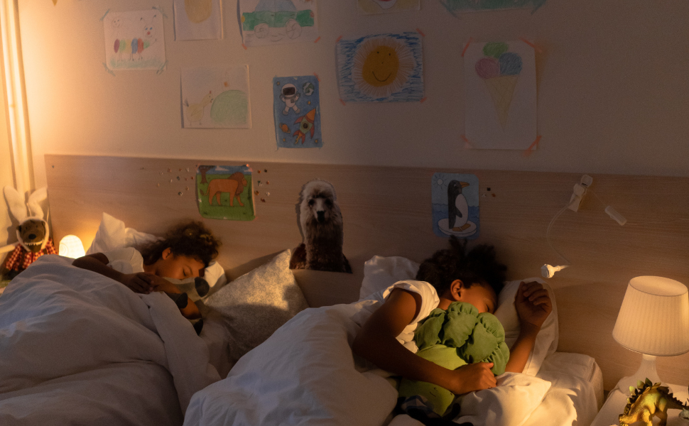 Two children sleeping in a bedroom. there are kids' drawings on the wall. Stability and safety are important for the growth and development of children. 