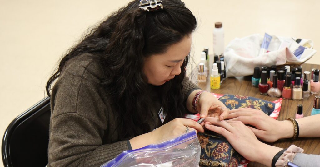 woman is giving a winter relief guest a manicure. Volunteers provide essential services people who are homeless often lack 
